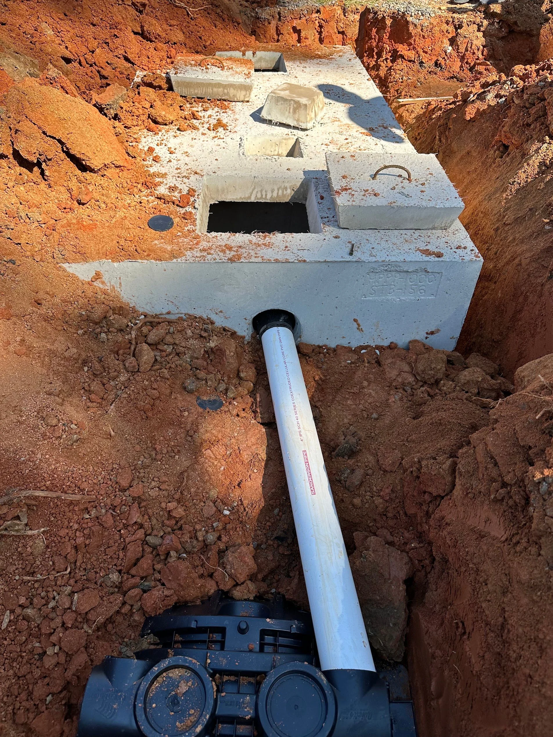 A newly installed septic tank and drainfield on a rural residential property outside Lincoln, Nebraska, with backfilled soil graded over the system and a cleared yard surrounding it. A KC Clearing and Septic crew truck is visible in the background near the excavation site.